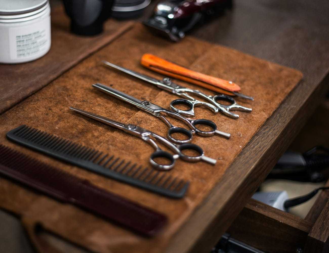 Barber tools on a table: scissors, combs, and a razor neatly arranged.